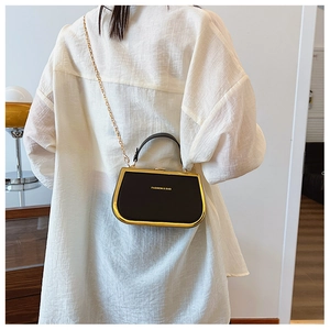 Detailed look at the black leather box bag with gold chain strap and metal clasp detail