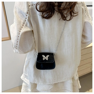 Vista posteriore di una modella con mini borsa a tracolla nera e farfalla argento