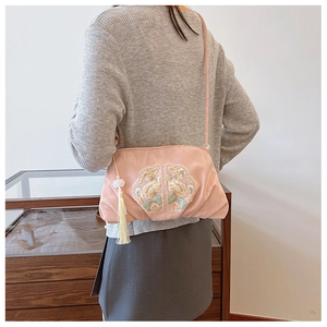 Details der rosa bestickten Handtasche mit weißer Quaste und traditionellem Blumenmuster
