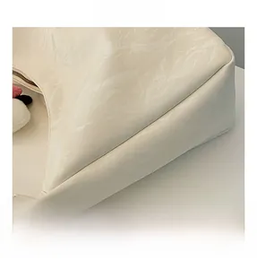 Detail shot of cream shoulder bag featuring wrinkled texture fabric and plush pendant