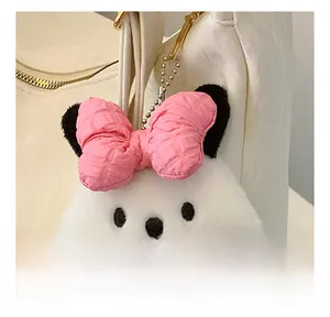 Cute white puppy plush charm with pink checkered bow and gold hook on a leather bag