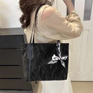 Elegante borsa tote nera plissettata con foulard alla moda indossata da una modella