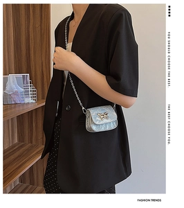 Détail du mini sac bandoulière argenté avec fermoir papillon et fine bandoulière