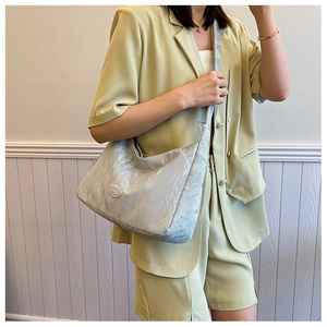 Detail of light gray pleated shoulder bag with oval logo on soft textured material