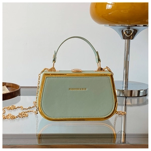 Detail of mint green hard shell handbag with gold clasp and Fashion & Bag lettering