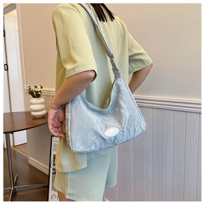 Detail of light grey pleated hobo bag with silky texture and oval logo patch