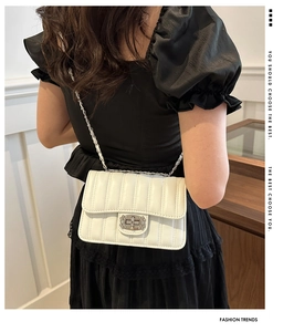 Close-up of white quilted chain bag with silver twist lock on a shoulder strap
