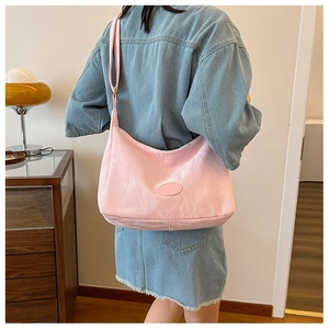 Light pink nylon crescent bag with adjustable strap shown on a person for scale