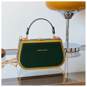 Detail of dark green box bag with gold metal frame and fashion engraving text