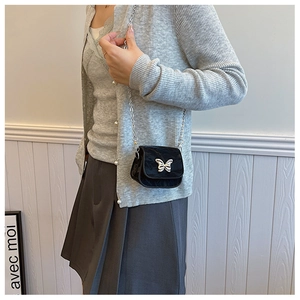 Détail du mini sac matelassé noir avec fermoir papillon argenté et bandoulière chaîne