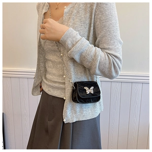 Détail du mini sac bandoulière en velours noir avec boucle papillon et bandoulière en perles