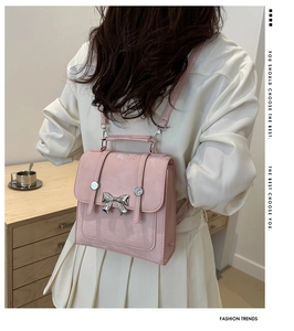 Close-up of pink leather bucket bag with silver metal bow detail and elegant matte finish