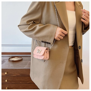 Détail du mini sac rose en cuir avec boucle papillon argentée et fine bandoulière chaîne