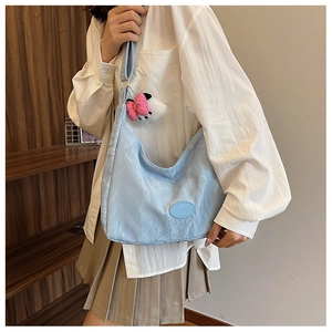 Detail of light blue textured hobo bag with adjustable strap and plush bow pendant