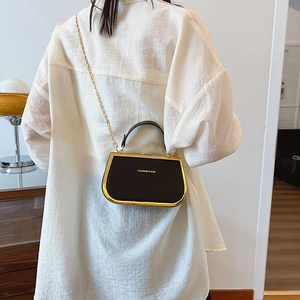 Mini chain box bag in black with gold metal frame shown on model for size perspective