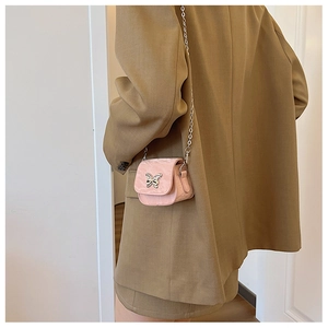 Vue détaillée d'un mini sac rose à chaîne avec ornement papillon et tissu brillant chic