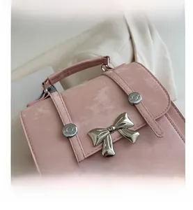 Detalle de bolso tipo cubo rosa con lazo plateado y textura mate de alta calidad suave