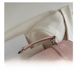 Detalle de bolso rosa con asa superior y anillas de metal plateado texturizado