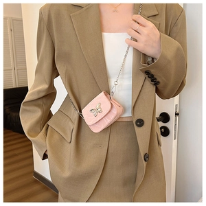 Gros plan du mini sac à bandoulière rose avec boucle papillon en métal sur un mannequin