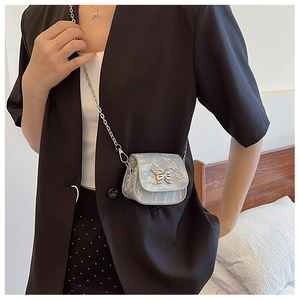 Détail du mini sac bandoulière avec boucle papillon argentée et texture marbrée