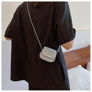 Gros plan d'un mini sac bandoulière bleu clair marbré avec papillon argenté et chaîne