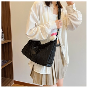 Detail of black nylon crescent bag with soft texture and cute plush cat pendant