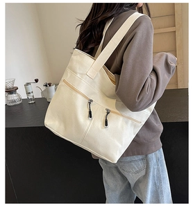 Lifestyle shot of a cream canvas tote bag with dual front zipper pockets on a model