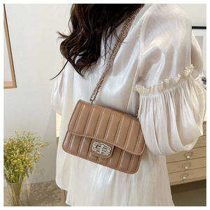 Detail of brown quilted chain bag with rhinestone lock and silver leather strap