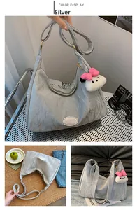 Detailed view of silver hobo bag with pleated texture and white plush pendant accessory