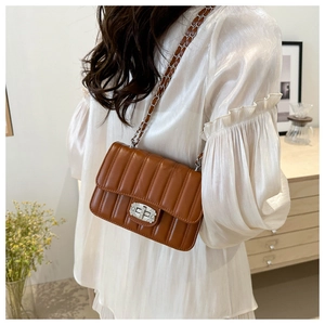 Detail of a brown quilted leather crossbody bag featuring a rhinestone-embellished silver lock