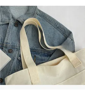 Detail of wide woven straps and durable cream canvas texture on the shoulder tote bag