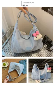 Detail of light blue hobo bag with pleated texture, gold zipper, and white bear charm