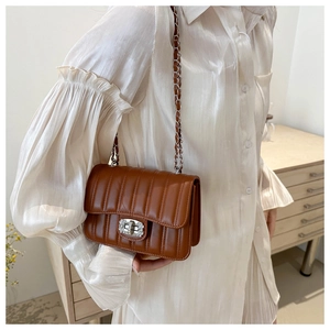 Detail of caramel quilted shoulder bag with silver chain strap and diamond-encrusted lock