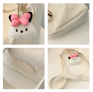 Macro detail of white pleated PU leather bag with cute plush pendant and gold hardware