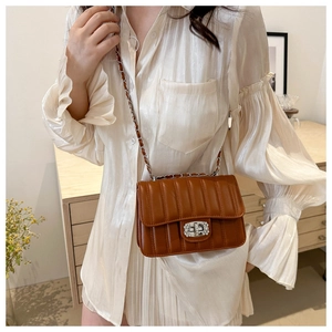 Detailed view of brown quilted bag featuring a crystal-encrusted rectangular twist lock