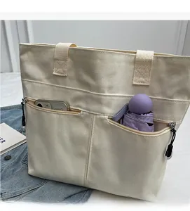 Detail of canvas tote bag front featuring two zippered pockets for phone and umbrella storage
