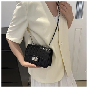 Detail of black quilted crossbody bag with crystal encrusted silver turn-lock and chain strap