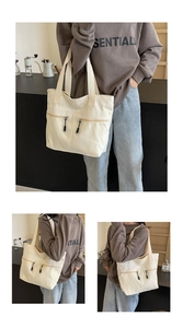 Detail view of cream canvas tote bag featuring parallel front zippers for daily commute