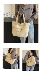 Detail view of beige canvas tote bag with functional dual metal zipper pockets and top handles