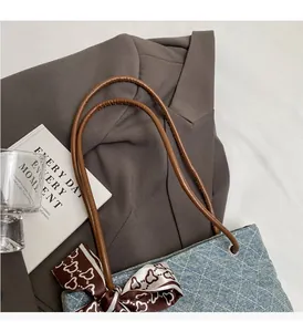 Dettaglio della borsa tote in denim blu con trapuntatura bianca e fiocco in seta marrone