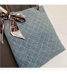 Dettaglio borsa tote in denim azzurro con cuciture bianche e foulard di seta decorativo