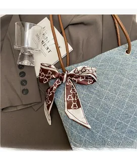 Dettaglio della tote in denim azzurro a quadri, manici in pelle e foulard con cuori