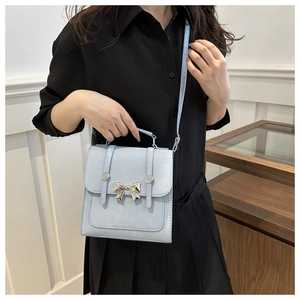 Lifestyle view of light blue crossbody bag with metallic butterfly and silver studs