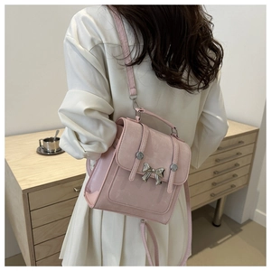 Detailed close-up of a pink mini backpack with a metallic butterfly and rivet accents
