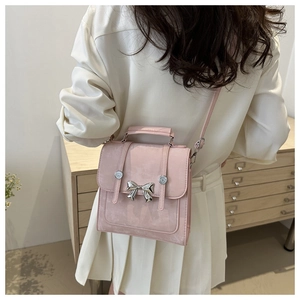 Détail du petit sac rose en cuir mat avec nœud papillon argenté et boutons métalliques