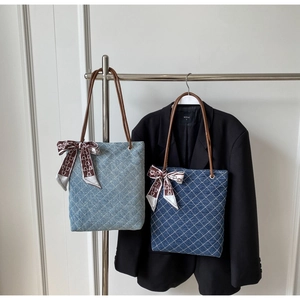 Dettaglio di borse tote in denim trapuntato con manici in pelle e foulard decorativi