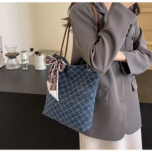 Dettaglio della borsa tote in denim blu con cuciture a rombi e sciarpa di seta decorativa