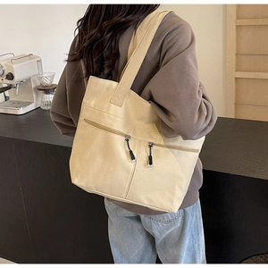 Detail view of large beige canvas tote bag with dual zipper pockets on the side