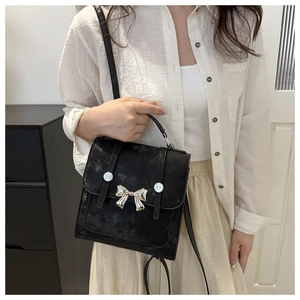 Primer plano de un bolso negro de estilo vintage con un detalle de lazo metálico plateado