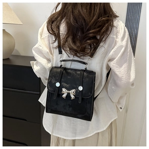 Close-up of black retro PU leather backpack with silver butterfly metal buckle detail